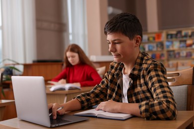 Photo of Boy using laptop at desk in public library