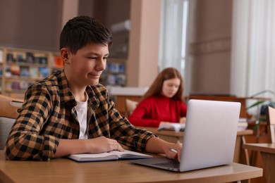 Photo of Boy using laptop at desk in public library