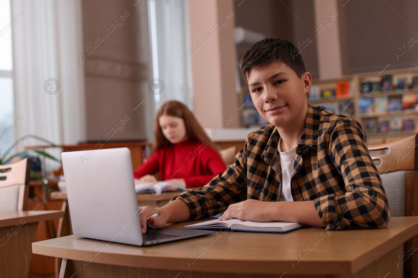 Photo of Boy using laptop at desk in public library