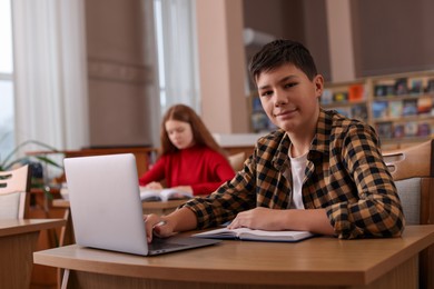 Photo of Boy using laptop at desk in public library