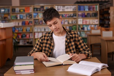 Photo of Boy reading book at wooden desk in public library