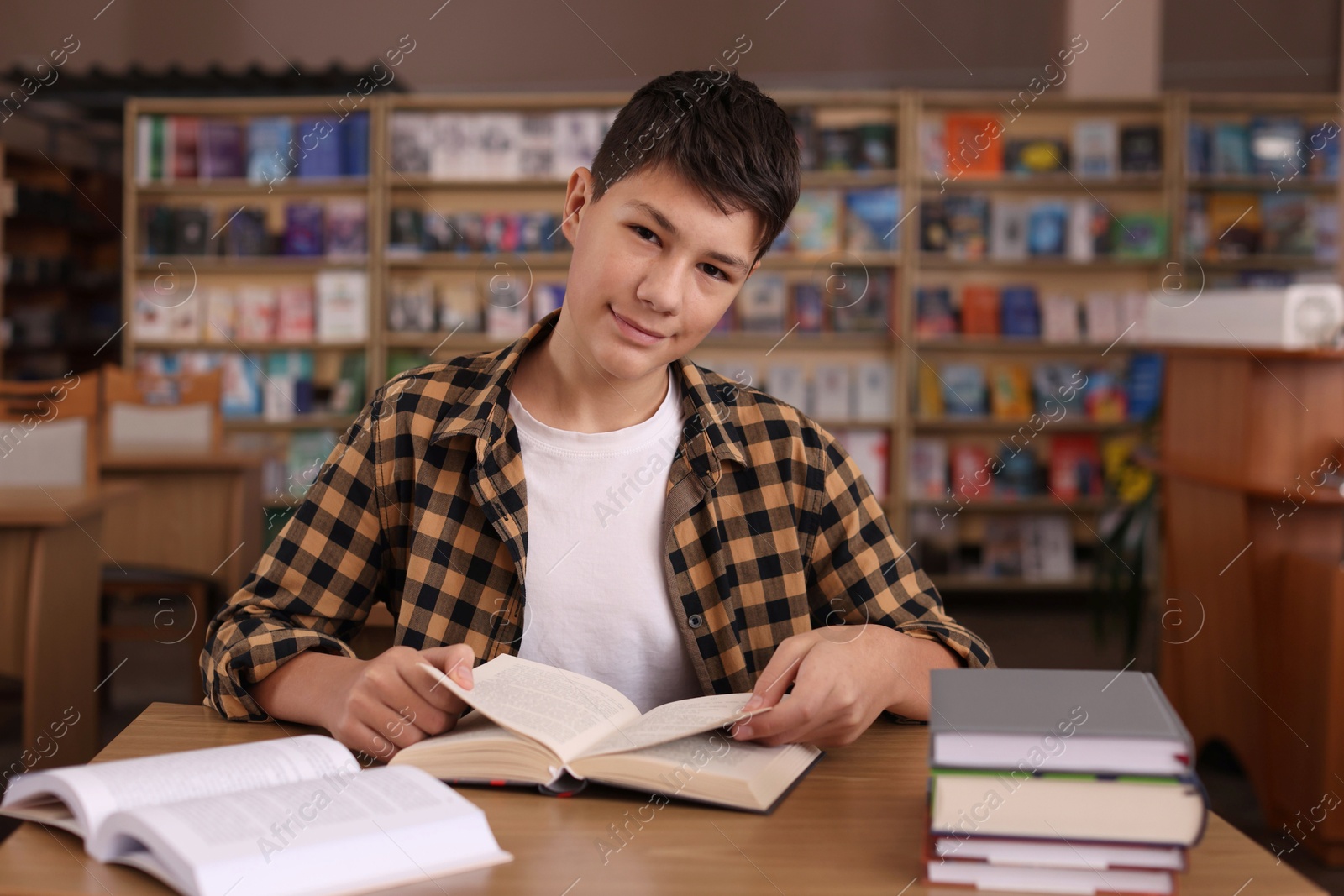 Photo of Boy reading book at wooden desk in public library