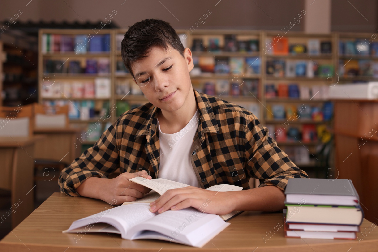 Photo of Boy studying at wooden desk in public library