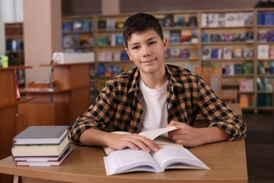 Photo of Boy studying at wooden desk in public library