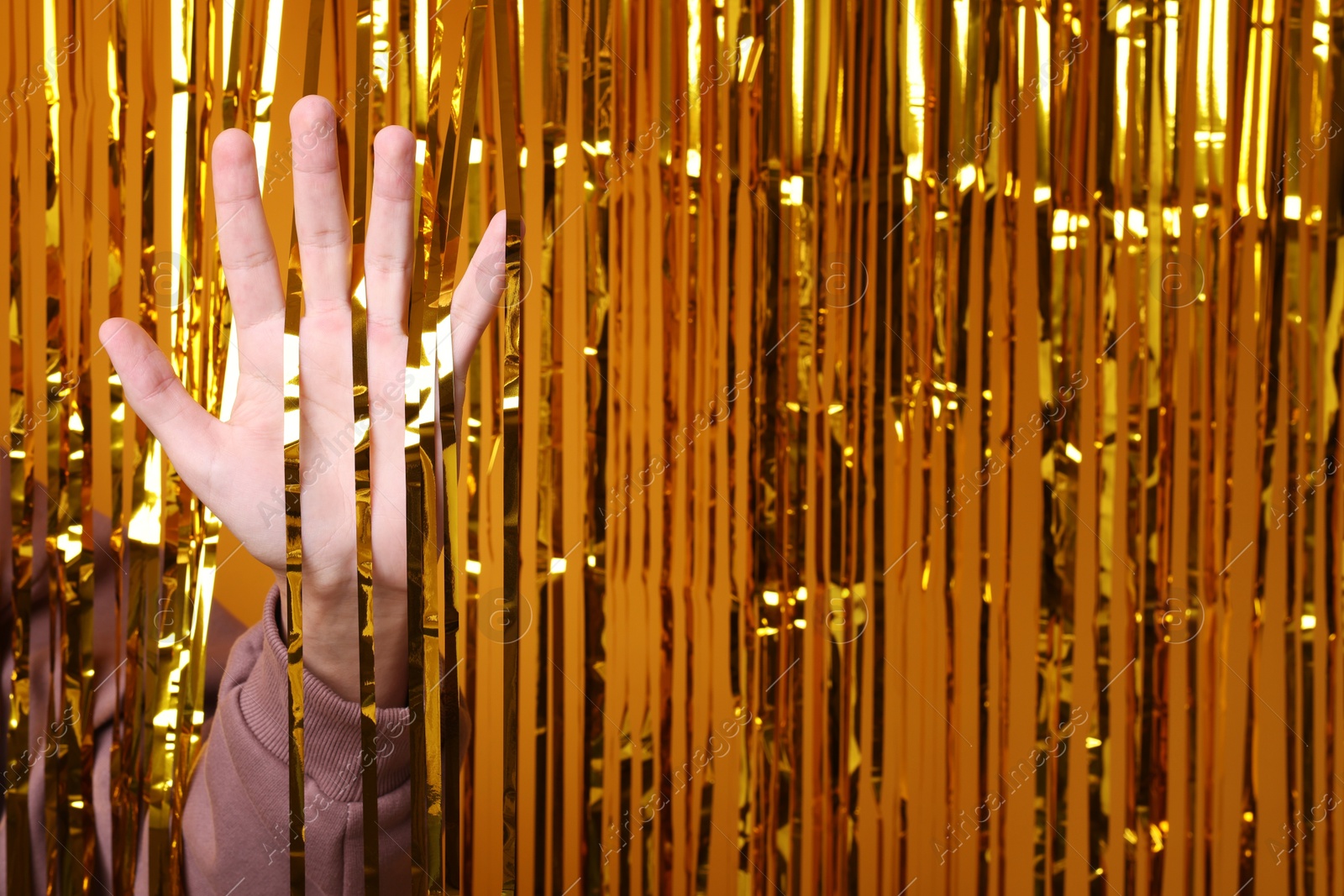 Photo of Man near golden foil curtain against orange background, closeup