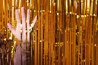 Photo of Man near golden foil curtain against orange background, closeup