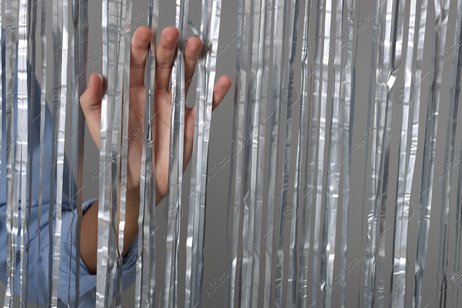 Photo of Man near silver foil curtain against light background, closeup