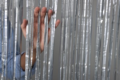 Photo of Man near silver foil curtain against light background, closeup