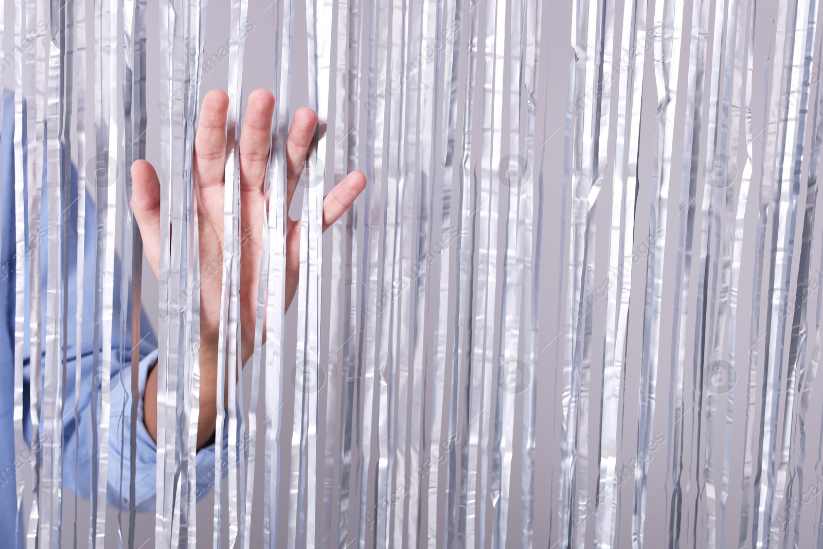 Photo of Man near silver foil curtain against light background, closeup