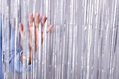 Photo of Man near silver foil curtain against light background, closeup