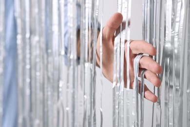 Photo of Man near silver foil curtain against light background, closeup