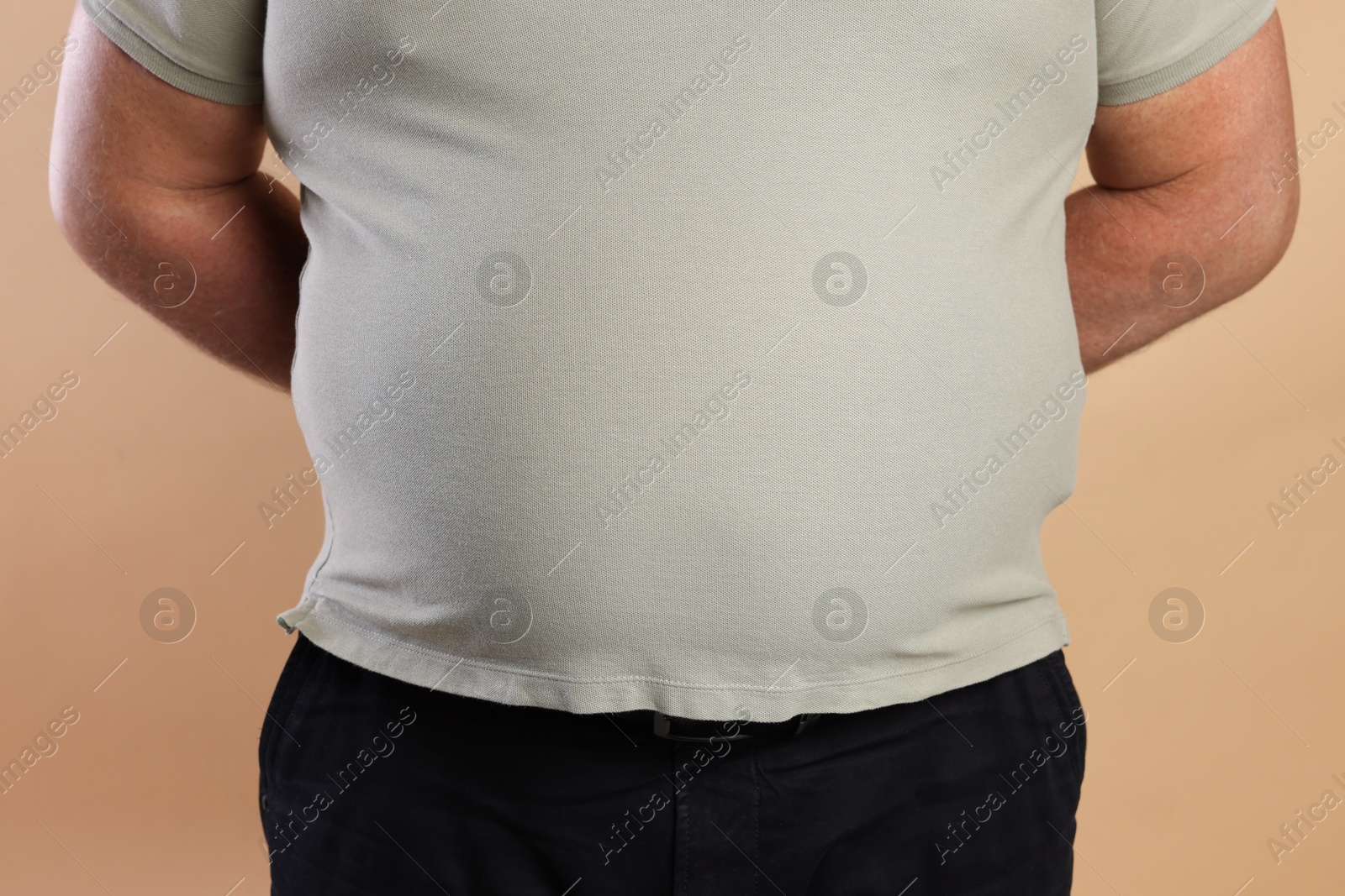 Photo of Overweight man in tight t-shirt on beige background, closeup