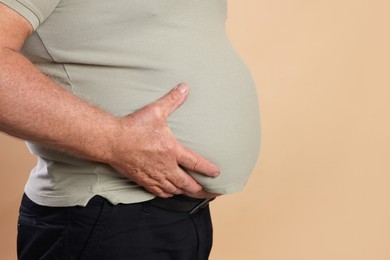 Photo of Overweight man in tight t-shirt on beige background, closeup. Space for text