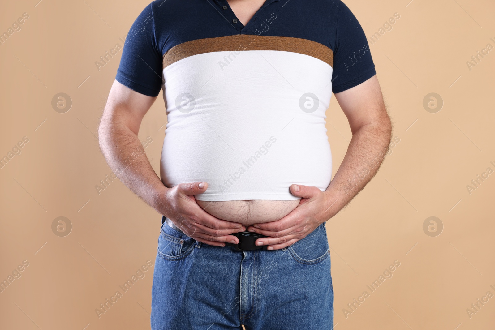 Photo of Overweight man in tight t-shirt on beige background, closeup