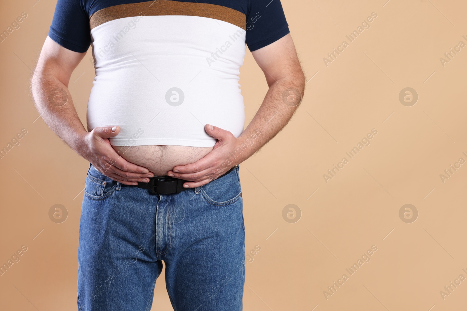 Photo of Overweight man in tight t-shirt on beige background, closeup. Space for text