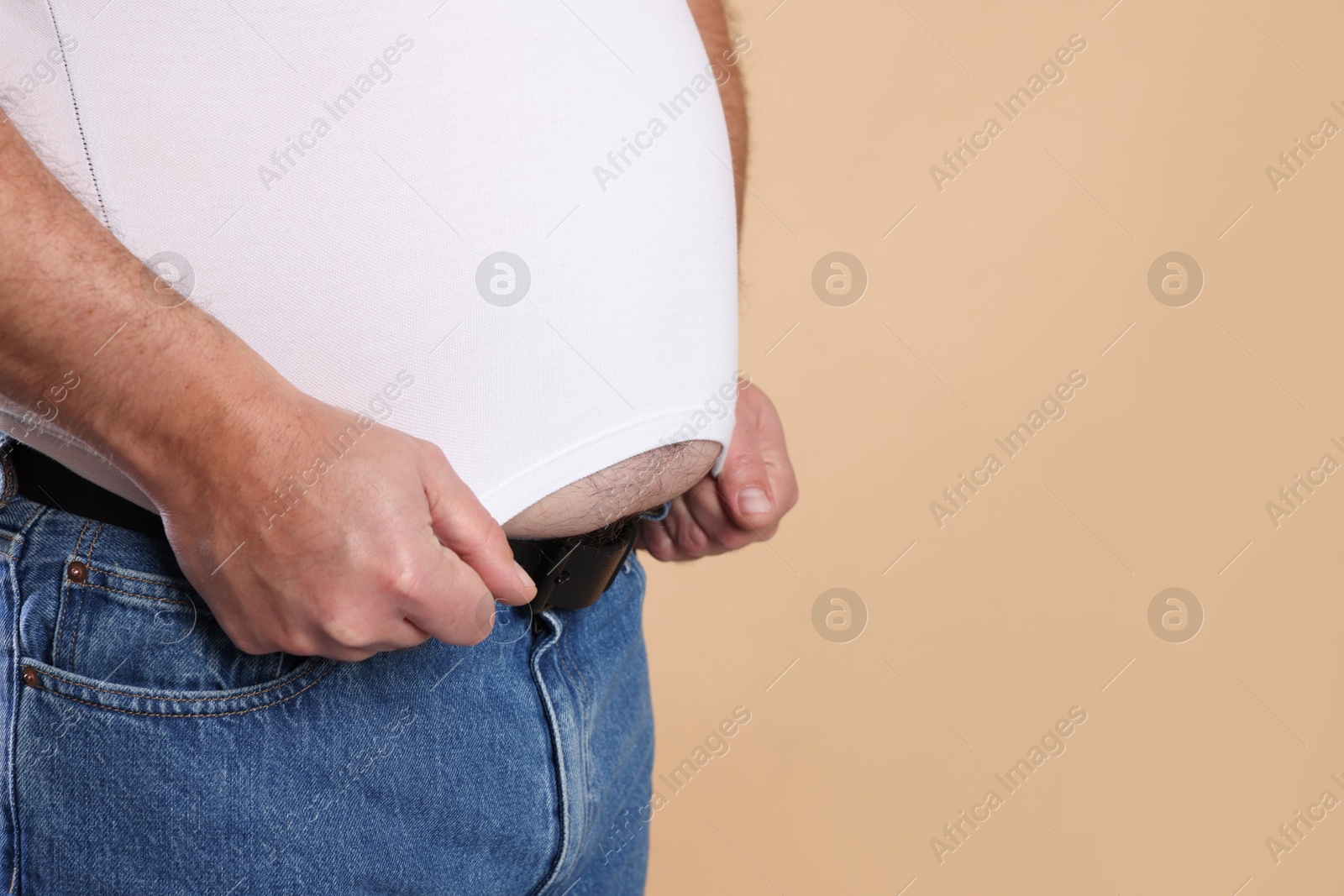 Photo of Overweight man in tight t-shirt on beige background, closeup. Space for text