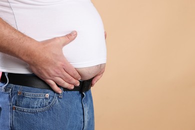 Photo of Overweight man in tight t-shirt on beige background, closeup. Space for text