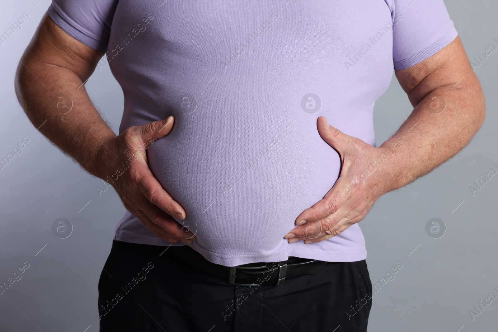 Photo of Overweight man in tight t-shirt on grey background, closeup