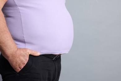 Photo of Overweight man in tight t-shirt on grey background, closeup. Space for text