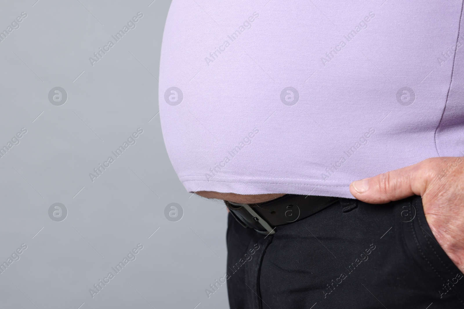 Photo of Overweight man in tight t-shirt on grey background, closeup. Space for text