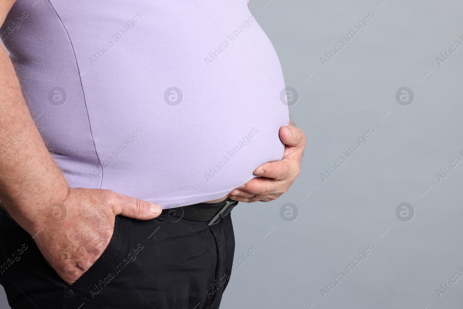 Photo of Overweight man in tight t-shirt on grey background, closeup. Space for text