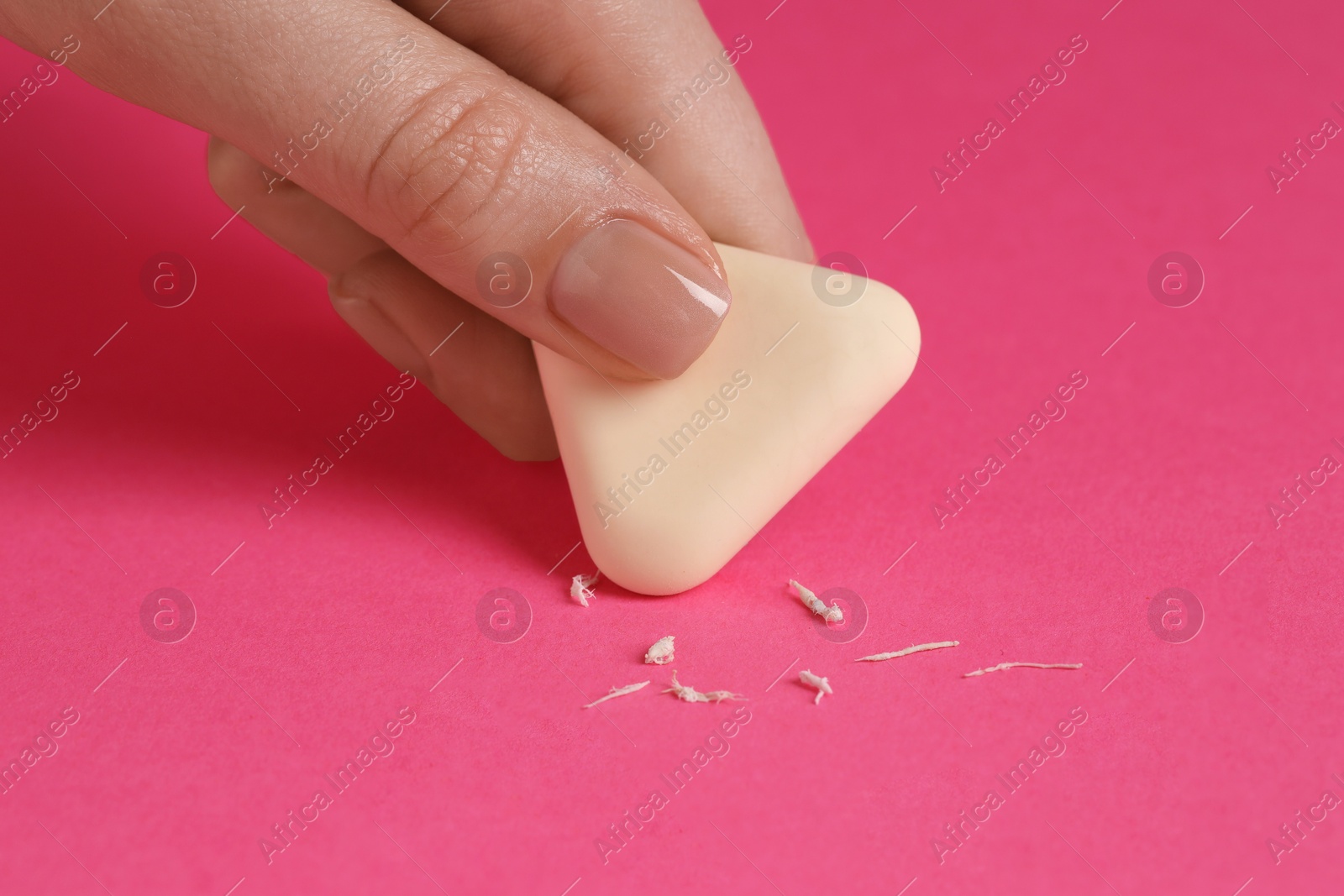 Photo of Woman using eraser on pink background, closeup