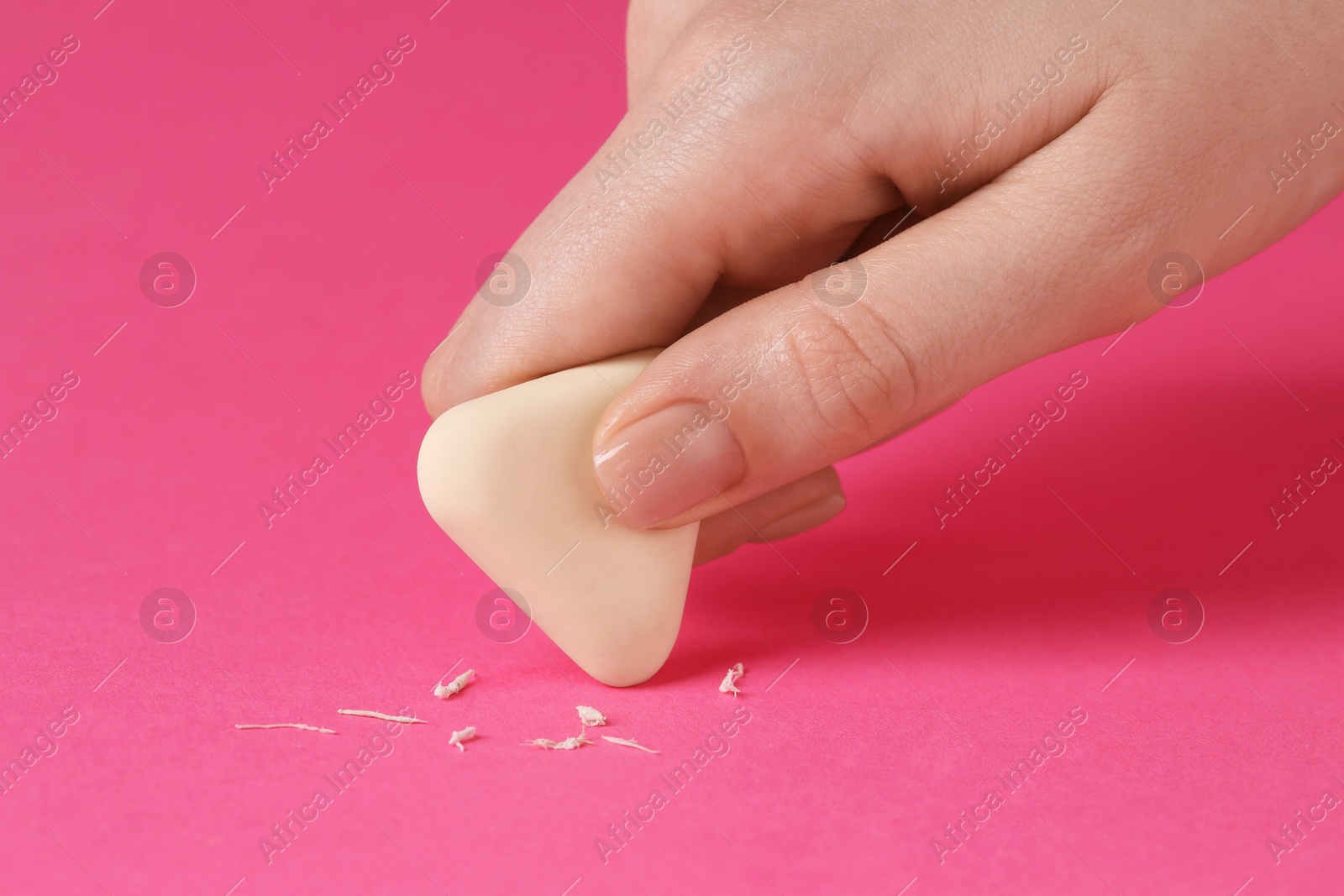 Photo of Woman using eraser on pink background, closeup