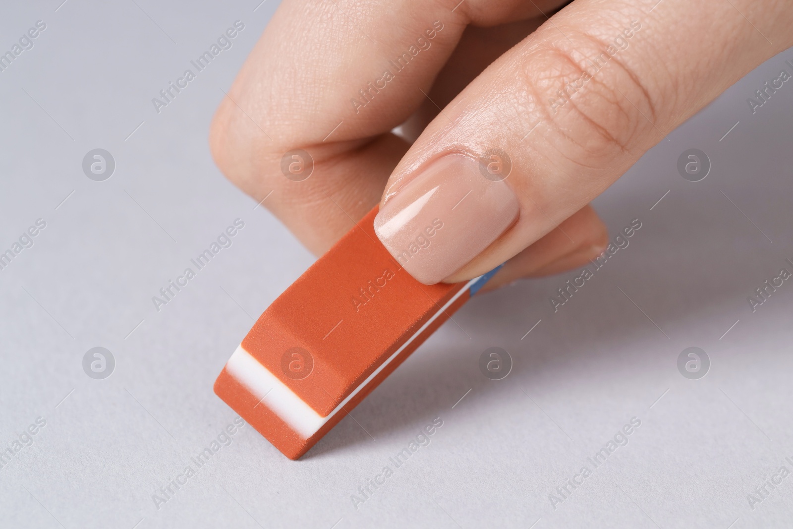 Photo of Woman using eraser on grey background, closeup