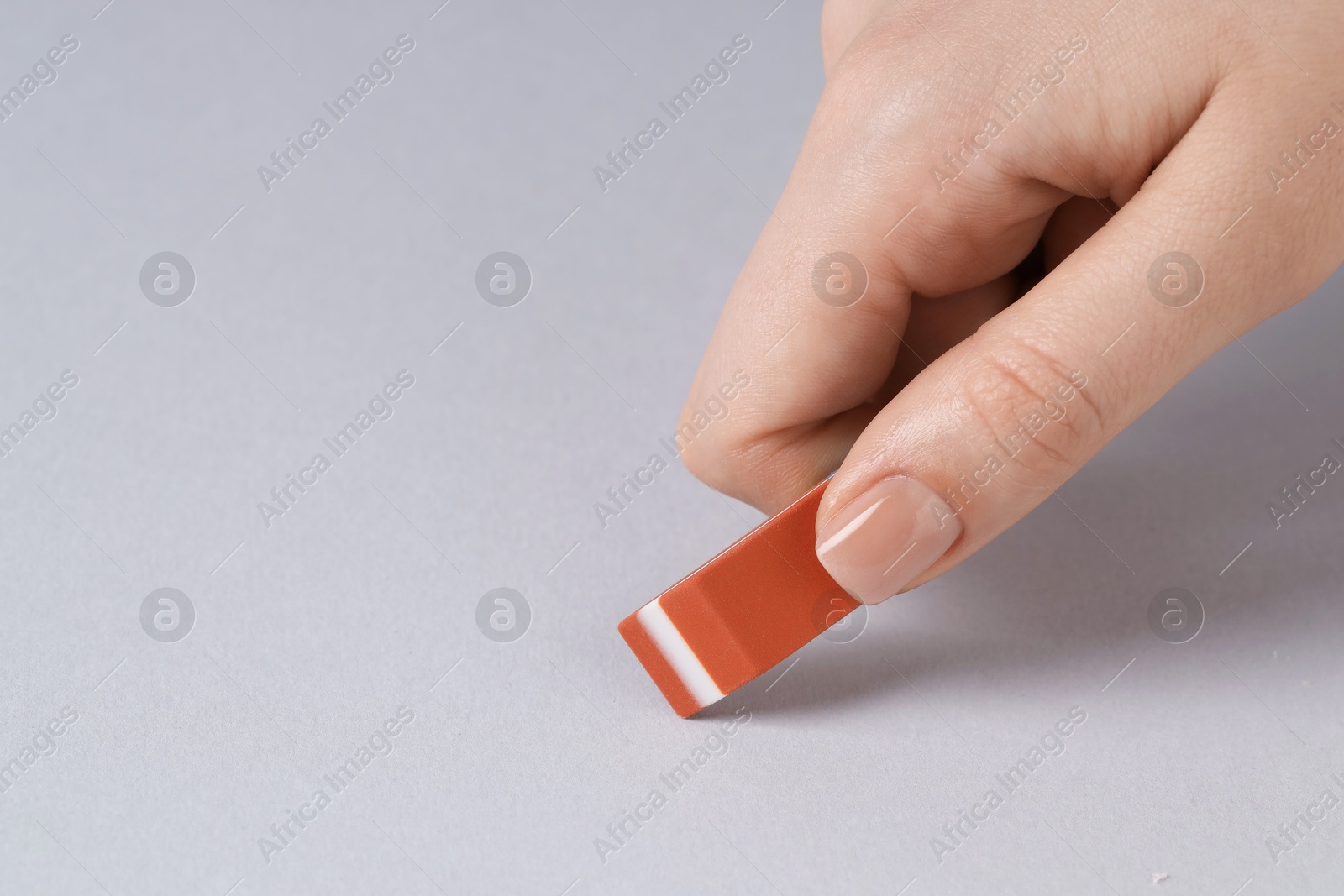 Photo of Woman using eraser on grey background, closeup. Space for text