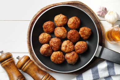 Photo of Tasty meatballs in frying pan and ingredients on white wooden table, flat lay