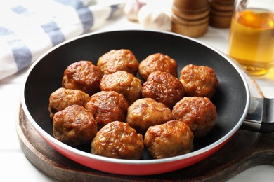 Photo of Tasty meatballs in frying pan on white table, closeup