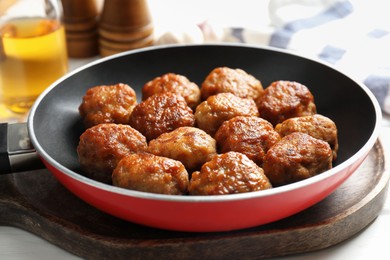 Photo of Tasty meatballs in frying pan on white table, closeup