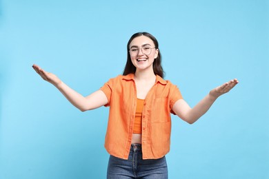 Photo of Happy woman welcoming friends or guests on light blue background