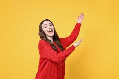 Photo of Happy woman welcoming friends or guests on yellow background