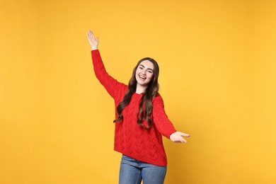 Photo of Happy woman welcoming friends or guests on yellow background