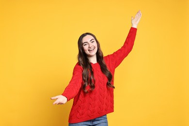 Photo of Happy woman welcoming friends or guests on yellow background