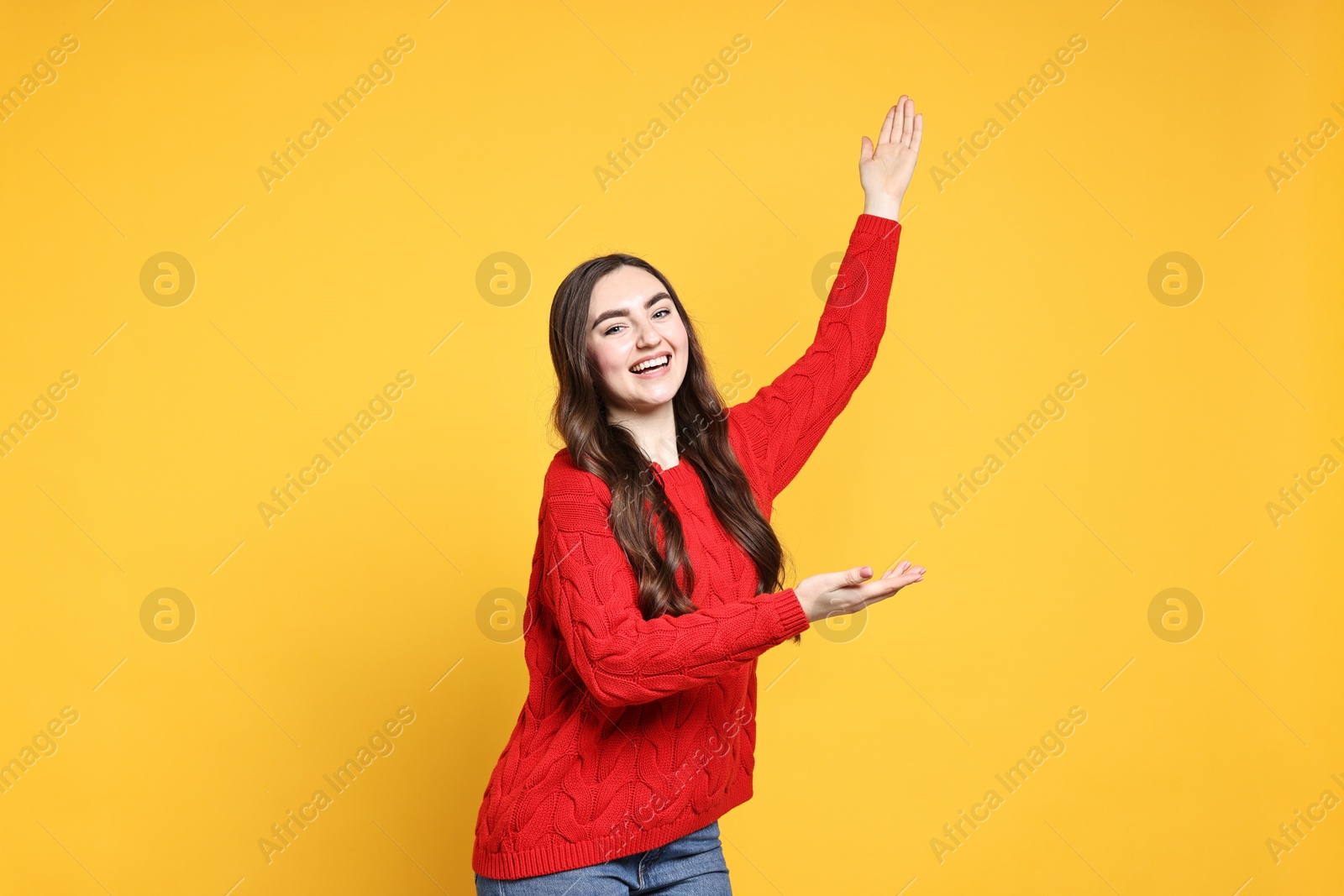 Photo of Happy woman welcoming friends or guests on yellow background