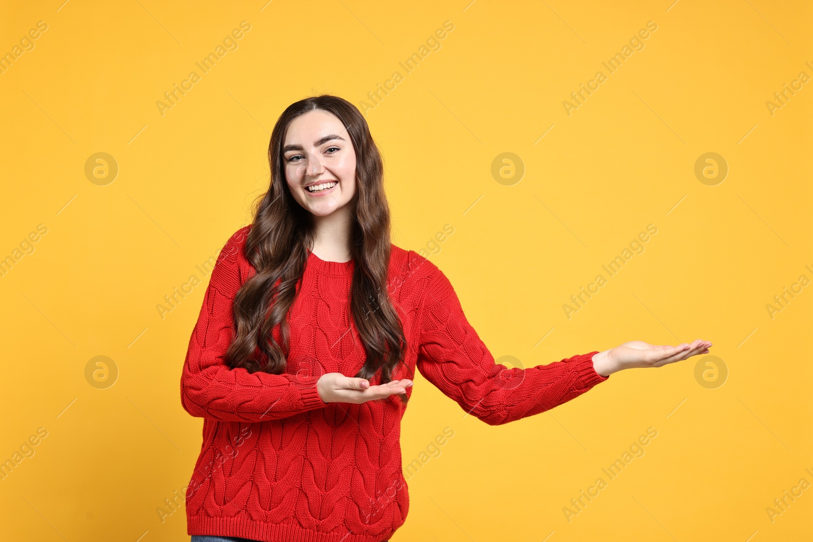 Photo of Happy woman welcoming friends or guests on yellow background