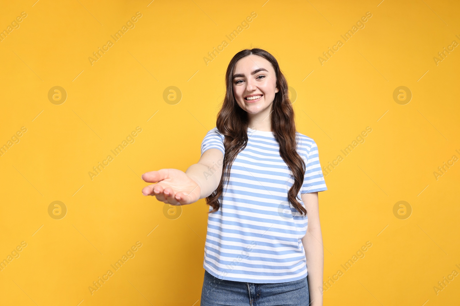 Photo of Happy woman welcoming friends or guests on yellow background, low angle view