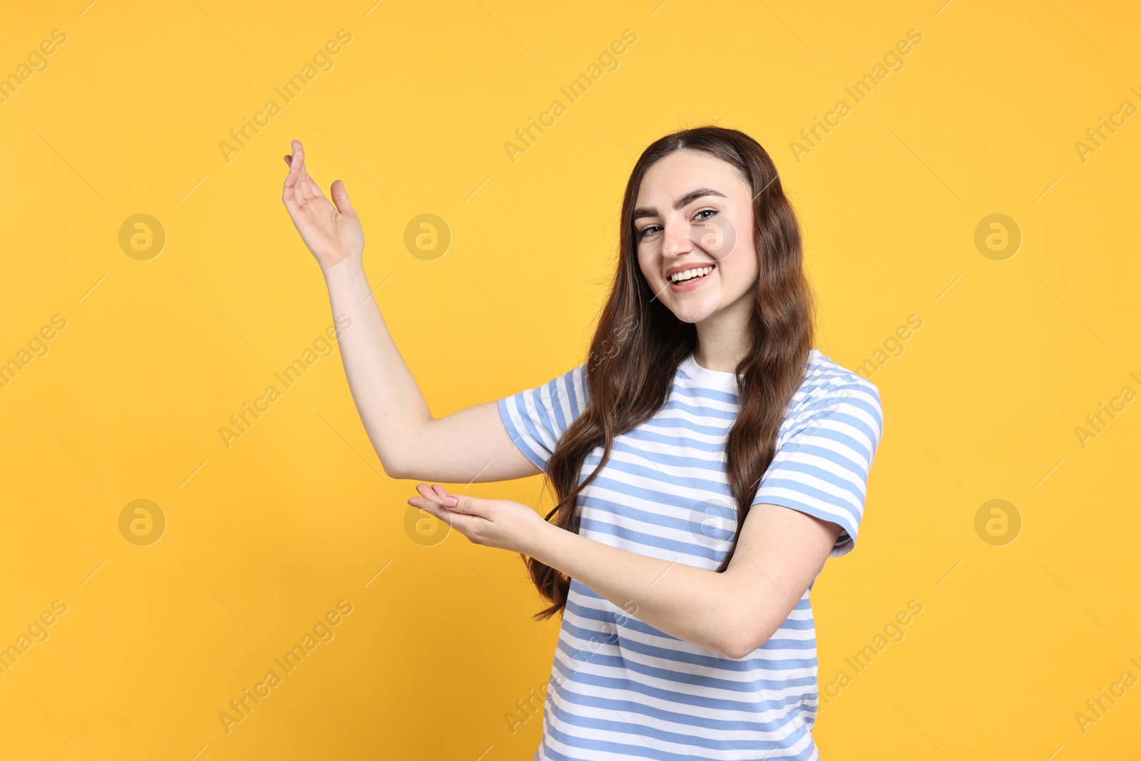 Photo of Happy woman welcoming friends or guests on yellow background