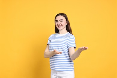 Photo of Happy woman welcoming friends or guests on yellow background