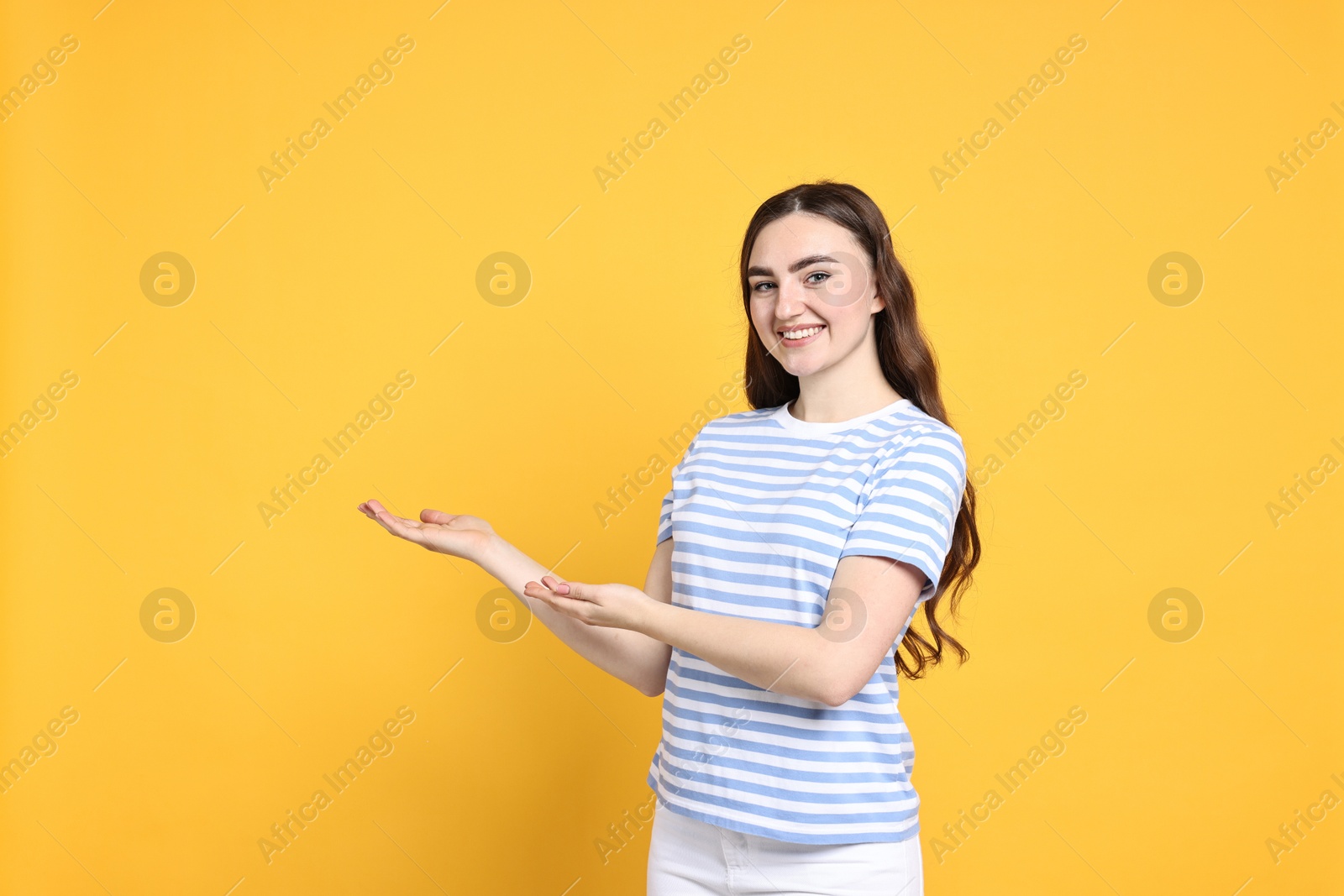 Photo of Happy woman welcoming friends or guests on yellow background