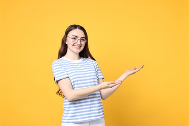 Photo of Happy woman welcoming friends or guests on yellow background