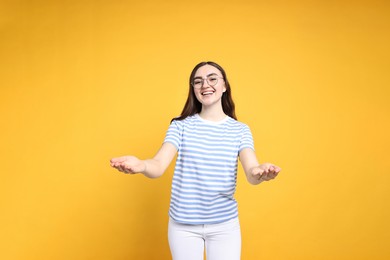 Photo of Happy woman welcoming friends or guests on yellow background