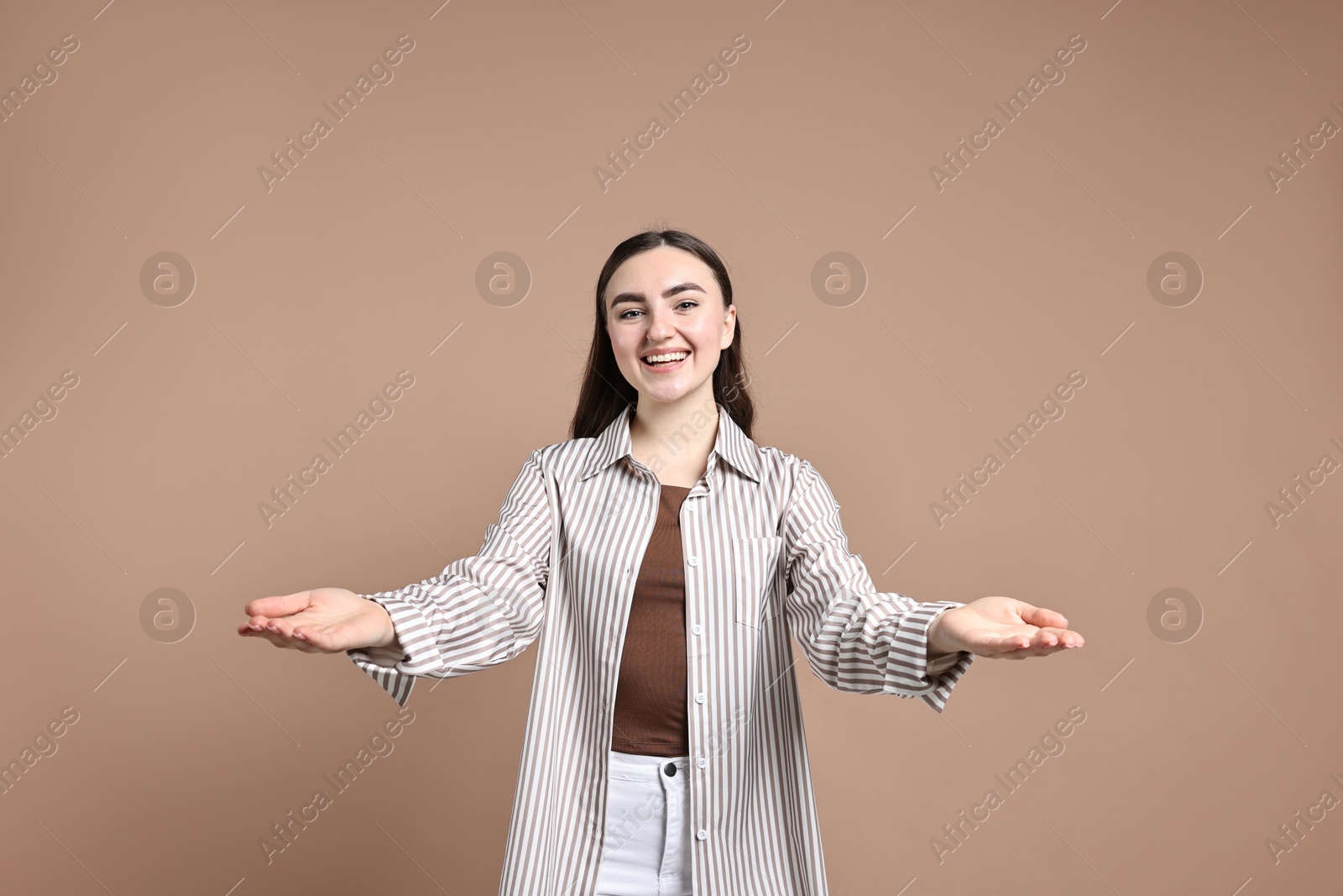 Photo of Happy woman welcoming friends or guests on beige background