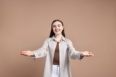 Photo of Happy woman welcoming friends or guests on beige background