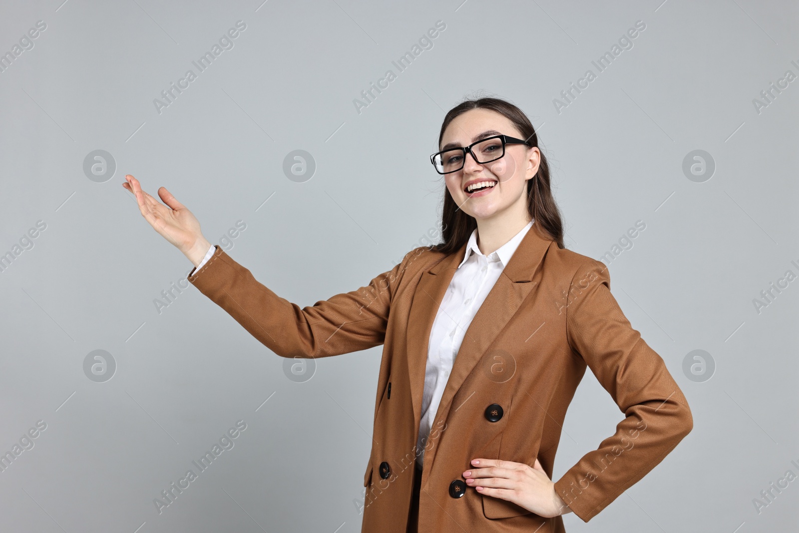 Photo of Happy businesswoman welcoming clients or partners on grey background