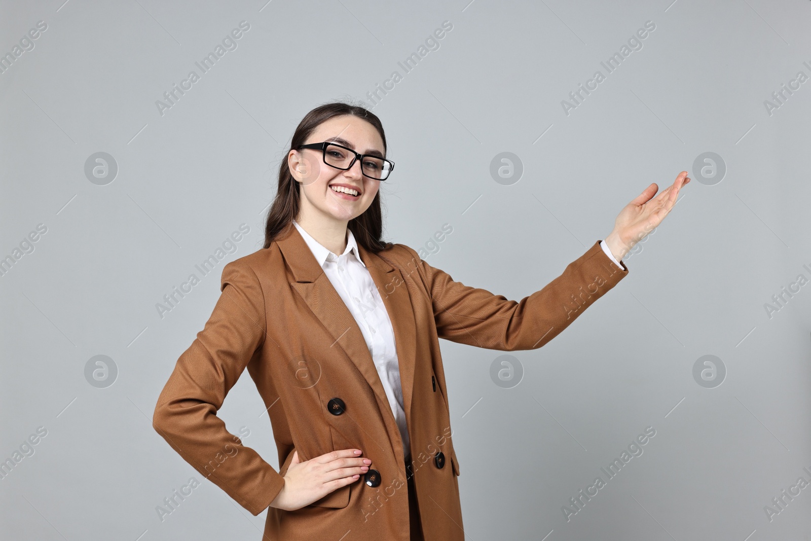 Photo of Happy businesswoman welcoming clients or partners on grey background