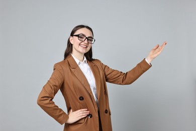 Photo of Happy businesswoman welcoming clients or partners on grey background