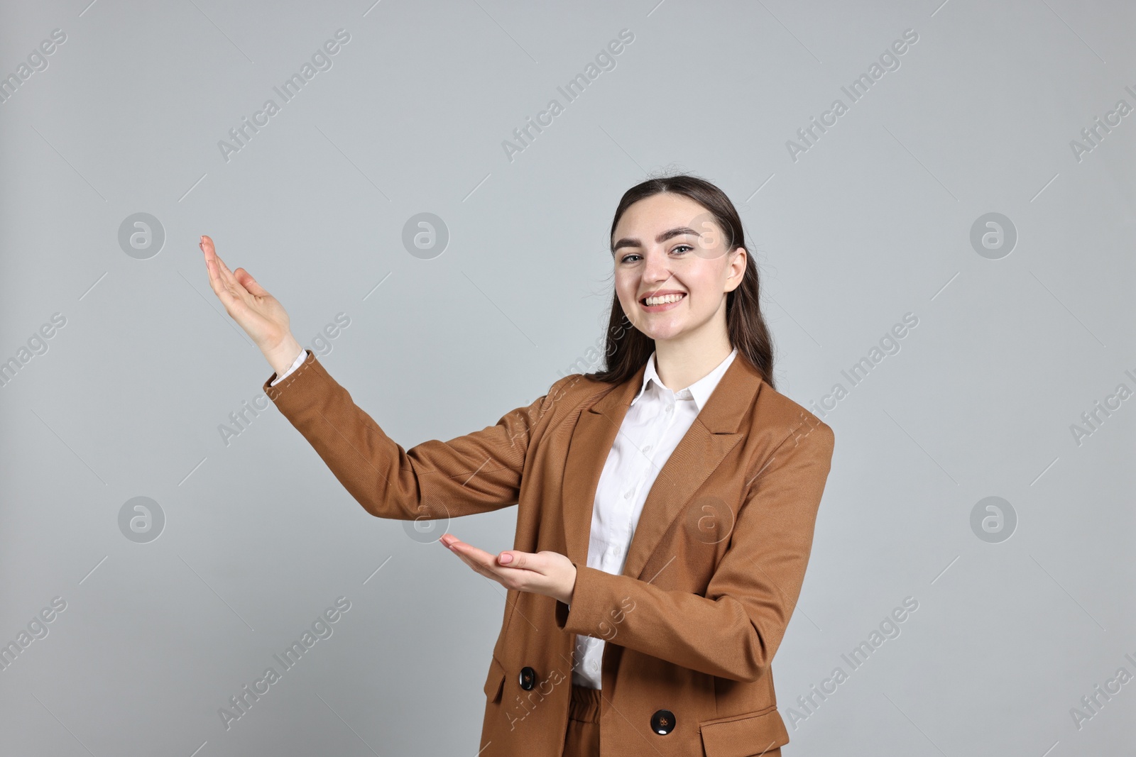 Photo of Happy businesswoman welcoming clients or partners on grey background